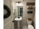 Stylish powder room with pedestal sink, decorative shelving, and modern fixtures at 2346 Upland Ln, Apopka, FL 32712