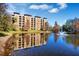 Building reflected in a tranquil lake with fountain at 12556 Floridays Resort Dr # 207-A, Orlando, FL 32821