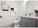 Modern bathroom with gray vanity, white toilet, and stylish artwork at 5197 Sw 155Th Loop, Ocala, FL 34473