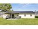 Back of house with solar panels, patio, and grassy yard at 8116 Powell Dr, Orlando, FL 32822