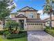 Two-story house with tan exterior, two-car garage, and manicured landscaping at 8920 Dove Valley Way, Davenport, FL 33896