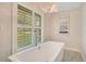 Relaxing bathroom with soaking tub, chandelier, and large window at 235 Oakdale St, Windermere, FL 34786