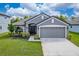 Gray house with a two-car garage and landscaping at 220 Bergamot Loop, Davenport, FL 33837