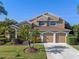 Two-story house with tan exterior, three-car garage, and palm trees at 1106 Kerwood Cir, Oviedo, FL 32765