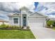 Charming house with gray siding, a white garage door, and well-maintained landscaping at 8632 Bridgeport Bay Cir, Mount Dora, FL 32757