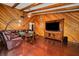 Living room with wood walls, hardwood floors, and a large TV at 894 Quarters Ct, Port Orange, FL 32129
