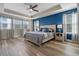 Main bedroom with blue accent wall, wood flooring, and large windows at 16328 Wind View Ln, Winter Garden, FL 34787