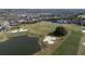 Aerial view of a residential golf course community with houses, a clubhouse and a lake at 12965 Trovita Dr, Grand Island, FL 32735