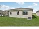 Single-story house back, featuring a covered patio, large windows, and a spacious grassy backyard at 12965 Trovita Dr, Grand Island, FL 32735