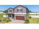 Two-story house with brown accents, solar panels, and a two-car garage at 556 Keyhold Loop, Apopka, FL 32712