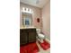 Clean bathroom with dark brown vanity, toilet and red rug at 301 Primrose Dr, Davenport, FL 33837