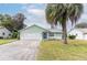 Light green house exterior with a two-car garage and palm tree at 16 Easter Ross Ct, Leesburg, FL 34788