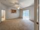 Spacious main bedroom with carpet, ceiling fan, and sliding glass doors to lanai at 24023 Robinwood St, Leesburg, FL 34748