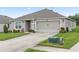 Tan house with gray roof, two-car garage, and landscaped lawn at 205 Bella Verano Way, Davenport, FL 33897
