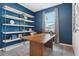 Home office with a wooden desk, built-in shelving, and blue walls at 5945 Cliffbow Loop, Leesburg, FL 34748