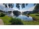 Scenic pond view with lush green grass and community buildings at 5600 Devonbriar Way # N202, Orlando, FL 32822