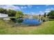 Serene pond with fountain, landscaping, and community buildings in background at 5600 Devonbriar Way # N202, Orlando, FL 32822