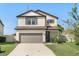 Two-story house with neutral siding, gray garage door, and manicured lawn at 1909 Cayman Cove Cir, St Cloud, FL 34772