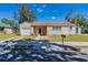 Tan house with red door, two-car driveway, and landscaped yard at 112 S Moss St, Leesburg, FL 34748
