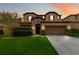 Two-story house with a brown garage door and lush green lawn at sunset at 5009 Torchwood Dr, Minneola, FL 34715