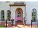 Elegant home entrance with a pink door, arched entryway, and potted plants at 2228 Azalea Pl, Winter Park, FL 32789
