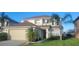 Two-story house with a beige garage door and palm trees at 115 Canna Dr, Davenport, FL 33897