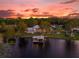 Luxury waterfront property showcasing a large home, pool, and private dock at sunset at 6320 S Sylvan Lake Dr, Sanford, FL 32771