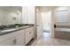 Bathroom with double sinks, granite countertop, and a soaking tub at 4537 Target Blvd, Kissimmee, FL 34746