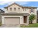 Two story house with beige exterior, shutters, and a two-car garage at 348 Sand Ridge Dr, Davenport, FL 33896