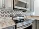 Stainless steel range and microwave complement granite countertop and patterned backsplash at 3623 Weatherfield Dr, Kissimmee, FL 34746