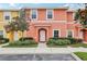 Two-story townhome with orange and yellow exterior, landscaping, and parking at 3004 Bird Of Paradise Ln, Kissimmee, FL 34747
