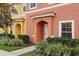 Two-story townhome with orange and yellow exterior, landscaping, and parking at 3004 Bird Of Paradise Ln, Kissimmee, FL 34747