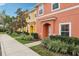 Two-story townhome with orange and yellow exterior, landscaping, and parking at 3004 Bird Of Paradise Ln, Kissimmee, FL 34747
