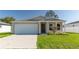Beige house with a white garage door and landscaping at 231 Begonia Ln, Kissimmee, FL 34759