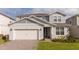 Two-story home with gray siding, white garage door, and landscaping at 5653 Oak Knoll Dr, St Cloud, FL 34771