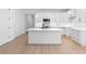 Modern white kitchen with an island, stainless steel appliances, and light wood floors at 4190 Rossmore Dr, Orlando, FL 32810