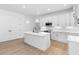 Modern white kitchen with an island, stainless steel appliances, and light wood floors at 4190 Rossmore Dr, Orlando, FL 32810