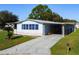 Single-wide manufactured home with carport, ramp, and landscaped yard at 202 Ellsworth Ct, Kissimmee, FL 34758