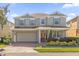 Two-story house with light beige siding, gray shutters, and a brick driveway at 621 Legacy Park Dr, Casselberry, FL 32707