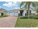 Single-story home with gray exterior, two-car garage, and brick driveway at 10071 Pecan Hickory Way, Orlando, FL 32832