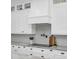White kitchen features a range hood, patterned backsplash, and sleek countertops at 4001 Ainsley Ave, Orlando, FL 32833