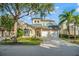 Two-story house with beige exterior, two-car garage, and landscaped front yard at 7491 Gathering Dr, Reunion, FL 34747