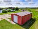 Red metal storage building with a large roll-up door, situated in a rural setting at 350 S 5Th St, Orlando, FL 32833