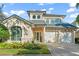 Two-story house with beige exterior, two-car garage, and landscaped front yard at 7491 Gathering Dr, Reunion, FL 34747