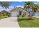 Tan house with a white garage door and palm trees at 1957 Teaberry Ct, Orlando, FL 32824