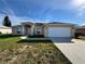 Tan one-story house with a white garage door and landscaped yard at 817 Highland Crest Loop, Lake Wales, FL 33853