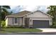 One-story home with gray siding, stone accents, and a two-car garage at 399 Eventide Ave, Mascotte, FL 34753