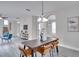 Open concept dining room, view from kitchen, with a rustic wooden table and modern light fixture at 7041 Buttonbush Loop, Harmony, FL 34773