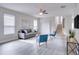 Bright living room with gray sofa, blue accent chairs, and ceiling fan at 7041 Buttonbush Loop, Harmony, FL 34773