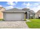 One-story home with gray siding, white garage door, and paved driveway at 12645 Crayford Ave, Orlando, FL 32837